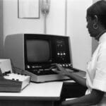 Womand sitting in front of a 1970's computer